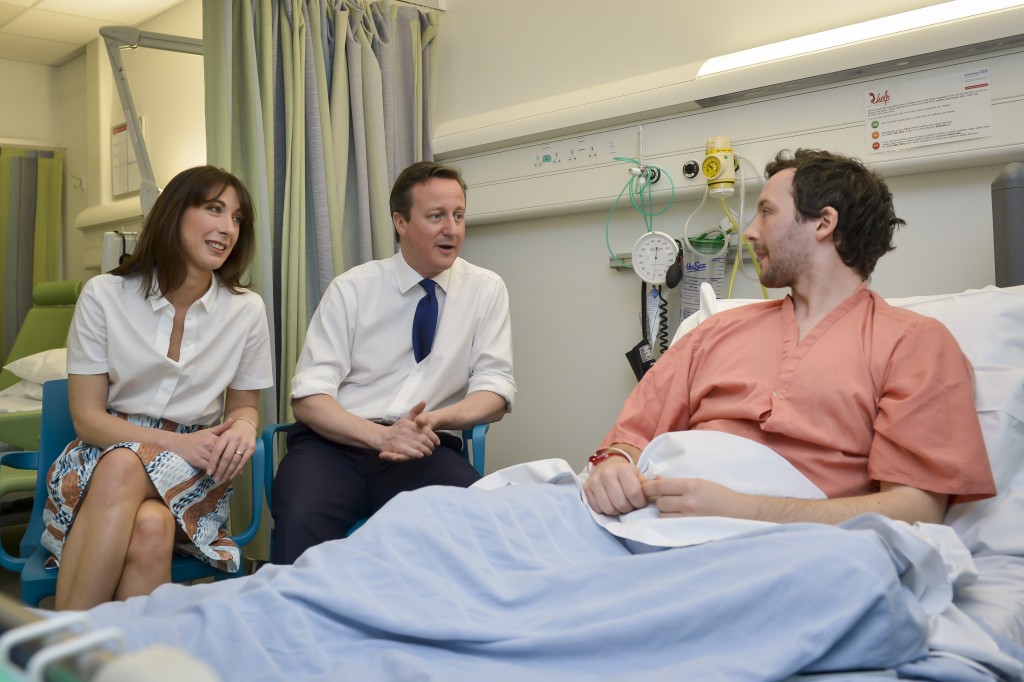 Prime Minister David Cameron and his wife Samantha Cameron talk with patient Tom Lawrence (right), 30, from Manchester, at his bedside, during a visit to the Salford Royal Hospital in Manchester, before speaking at the Conservative Spring Forum.